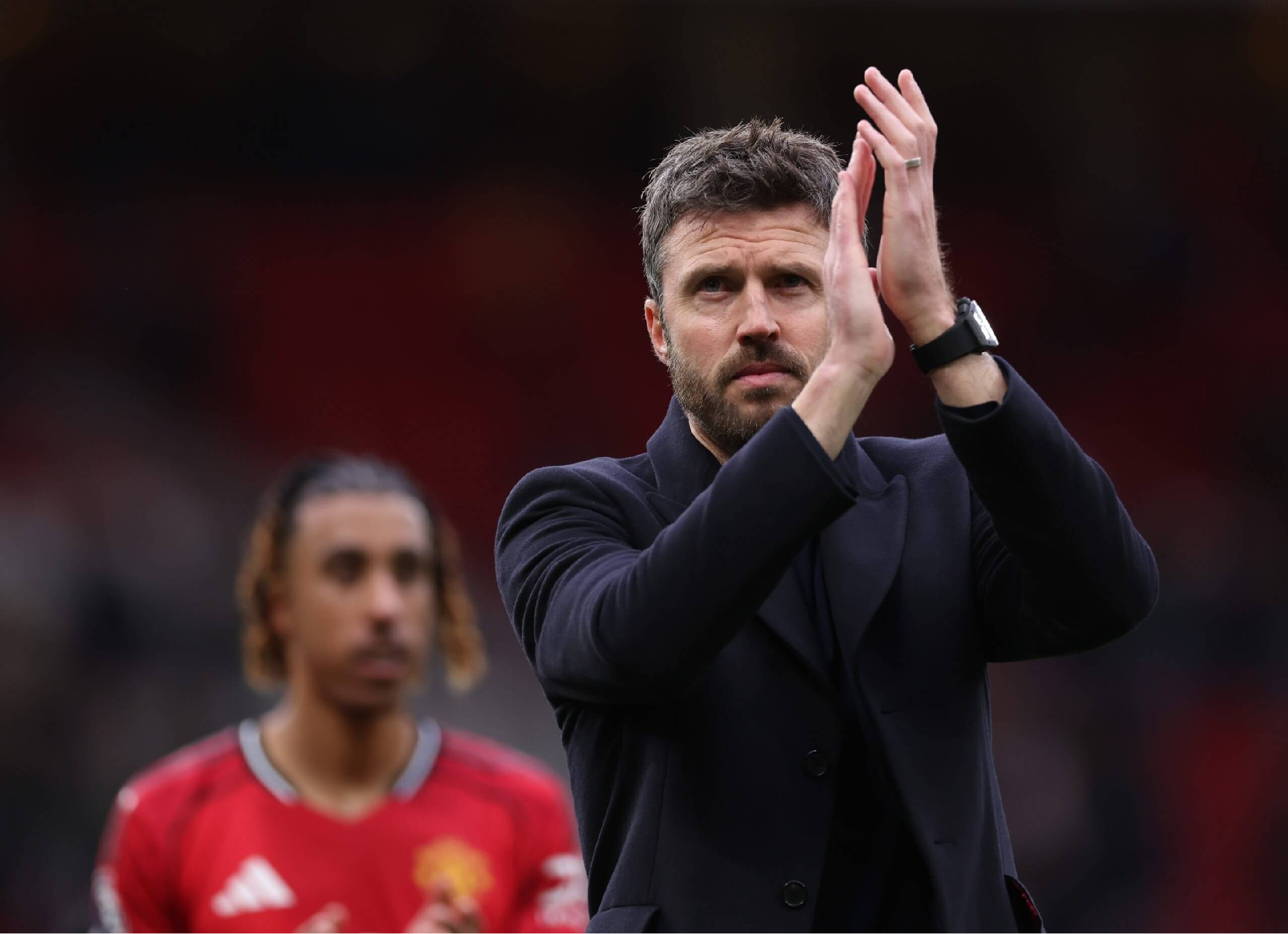 Michael Carrick wearing a mid-thigh black wool-blend overcoat on the touchline during West Ham United vs Manchester United Premier League match, showcasing sleek tailored fit and elegant stadium style.