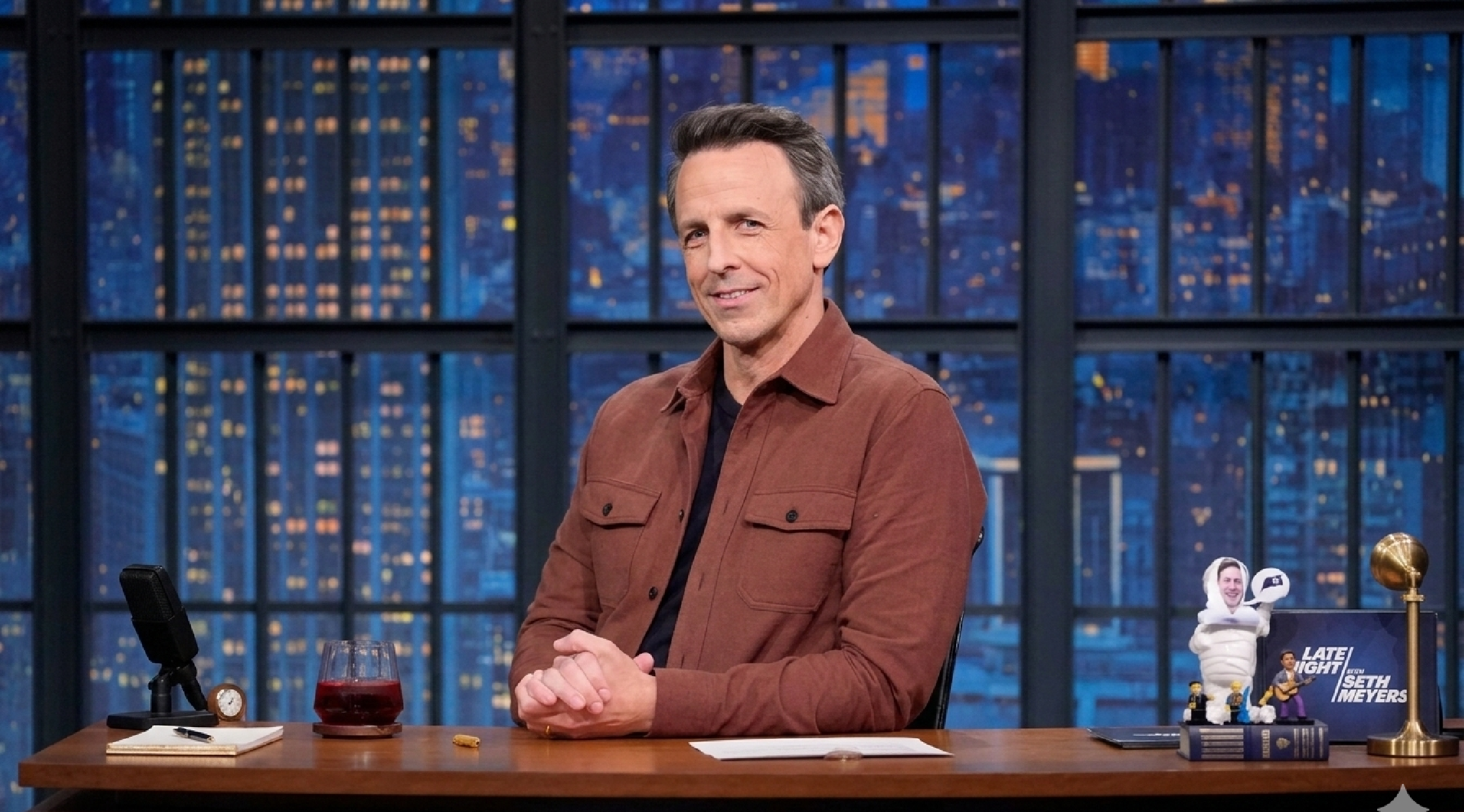 Seth Meyers wearing a rust-brown terracotta overshirt with oversized chest pockets and a point collar over a black crewneck on the Late Night with Seth Meyers set, Season 13, March 3, 2026.
