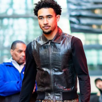 Jared McCain wears a sleek black leather vest over a long-sleeved shirt, blending high-fashion style with basketball energy.