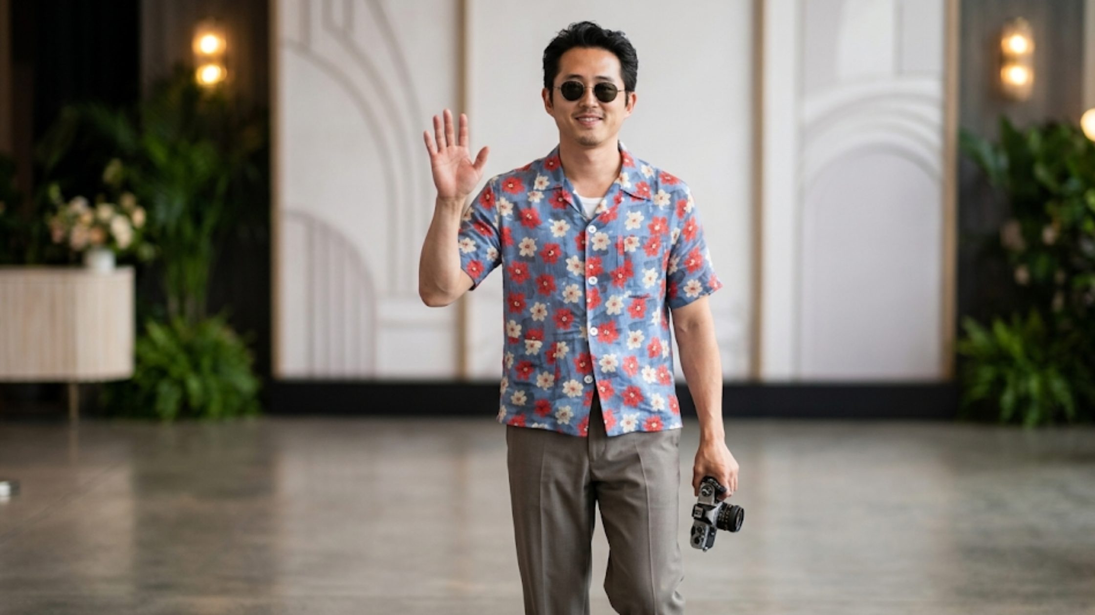 Steven Yeun Netflix Tudum 2025 colorful tropical floral button-up shirt with blue base and vibrant botanical print