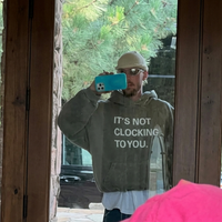 It’s Not Clocking To You moss green oversized hoodie with bold white typography print and fleece fabric for streetwear style