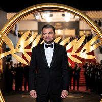 Leonardo DiCaprio wearing a black tuxedo at the 78th Cannes Film Festival opening ceremony, featuring a slim-fit jacket, satin peak lapels, white dress shirt, and black bow tie.