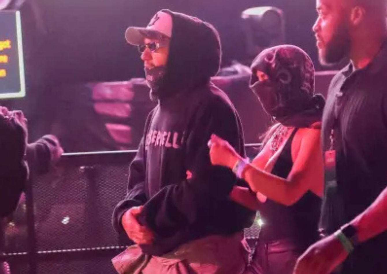 Lewis Hamilton wearing an oversized black BIEBERVELLI hoodie with cropped fit and kangaroo pocket at Coachella 2026 next to Kim Kardashian