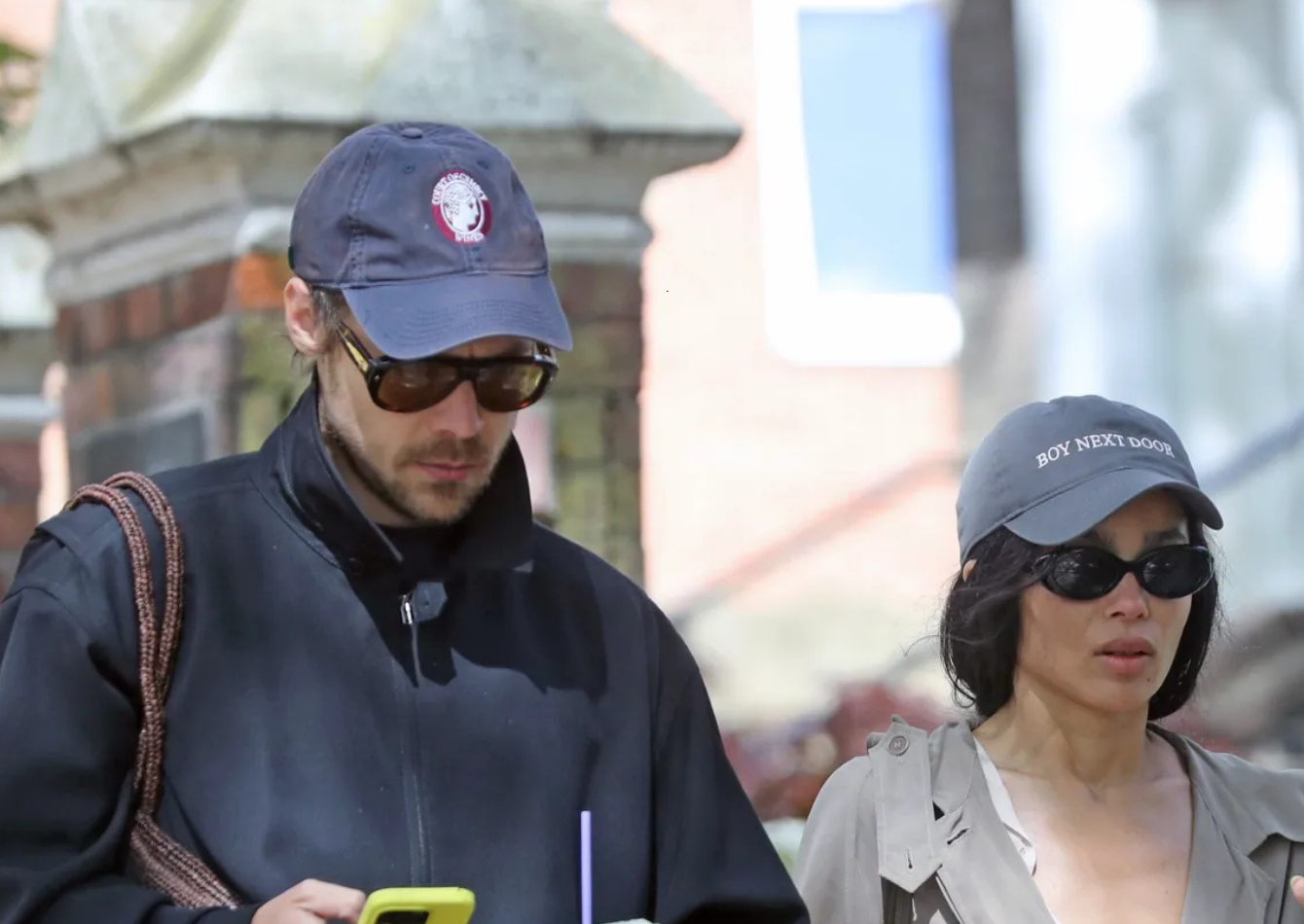 Harry Styles wearing a navy Harrington jacket and Zoë Kravitz in a khaki-gray trench coat during a coordinated London street style outing