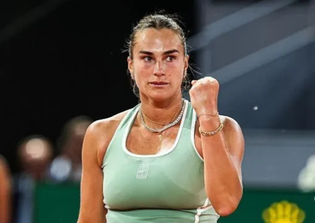 Aryna Sabalenka wears a mint green NikeCourt tennis dress with white accents and gold jewelry during the Mutua Madrid Open 2026 on a red clay court.