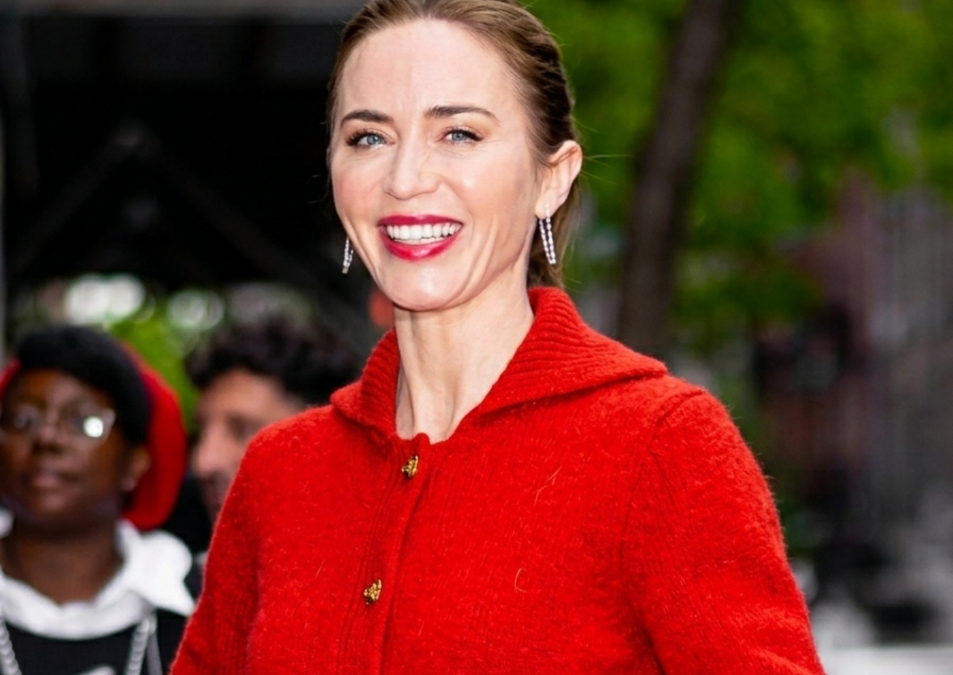 Emily Blunt wearing a bright red cropped wool cardigan with gold buttons and patch pockets at The Devil Wears Prada 2 NYC 2026 screening in New York City