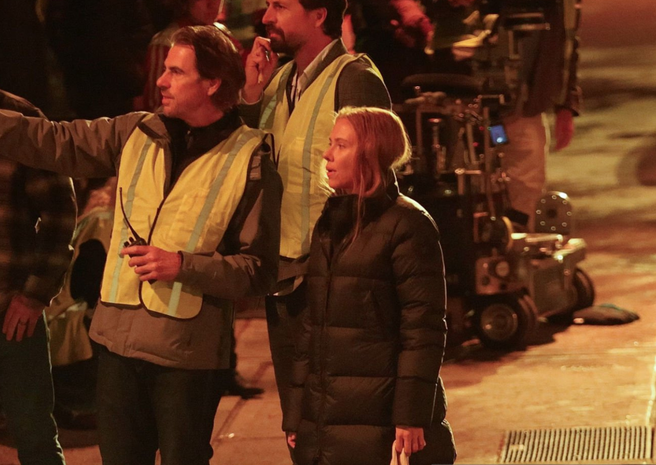 Scarlett Johansson wearing a black floor-length quilted puffer coat with high collar on The Exorcist NYC 2026 film set in Queens