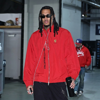 Jordan Clarkson wearing a red Porsche windbreaker jacket with silver zipper, oversized fit, and bold streetwear style at an NBA game arrival