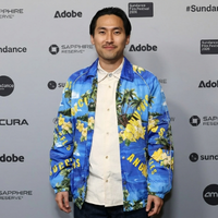 Jin Ha 2026 Sundance Film Festival blue bomber jacket with tropical palm tree and hibiscus floral print, white piping, silver snap buttons, and bold luxury streetwear typography design.