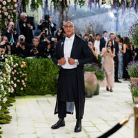 Dwayne Johnson wearing a custom Thom Browne black floor-length mohair overcoat with silk lapels and pleated detailing at the 2026 Met Gala red carpet.