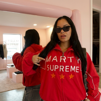 Valentina Voight Marty Supreme cherry red windbreaker jacket featuring oversized graphic lettering, star detailing, white piping accents, and a relaxed vintage-inspired sportswear street style silhouette.