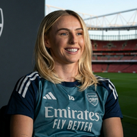 Chloe Kelly Arsenal FC teal training jersey featuring navy sleeves, white Arsenal crest, Emirates Fly Better logo, and modern athletic color-blocked football styling.