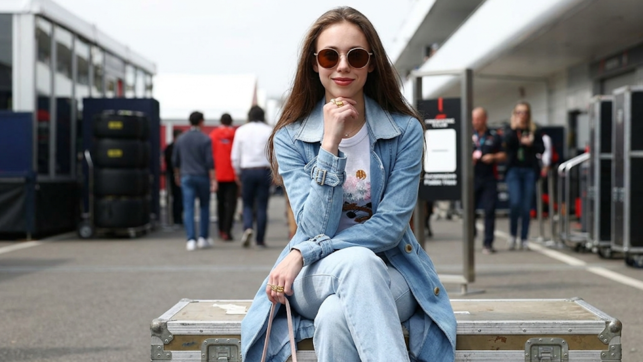 Lily Zneimer 2026 Japanese Grand Prix denim trench coat light-wash blue mid-length double-breasted outfit with sunglasses and cherry blossom T-shirt Suzuka F1 style
