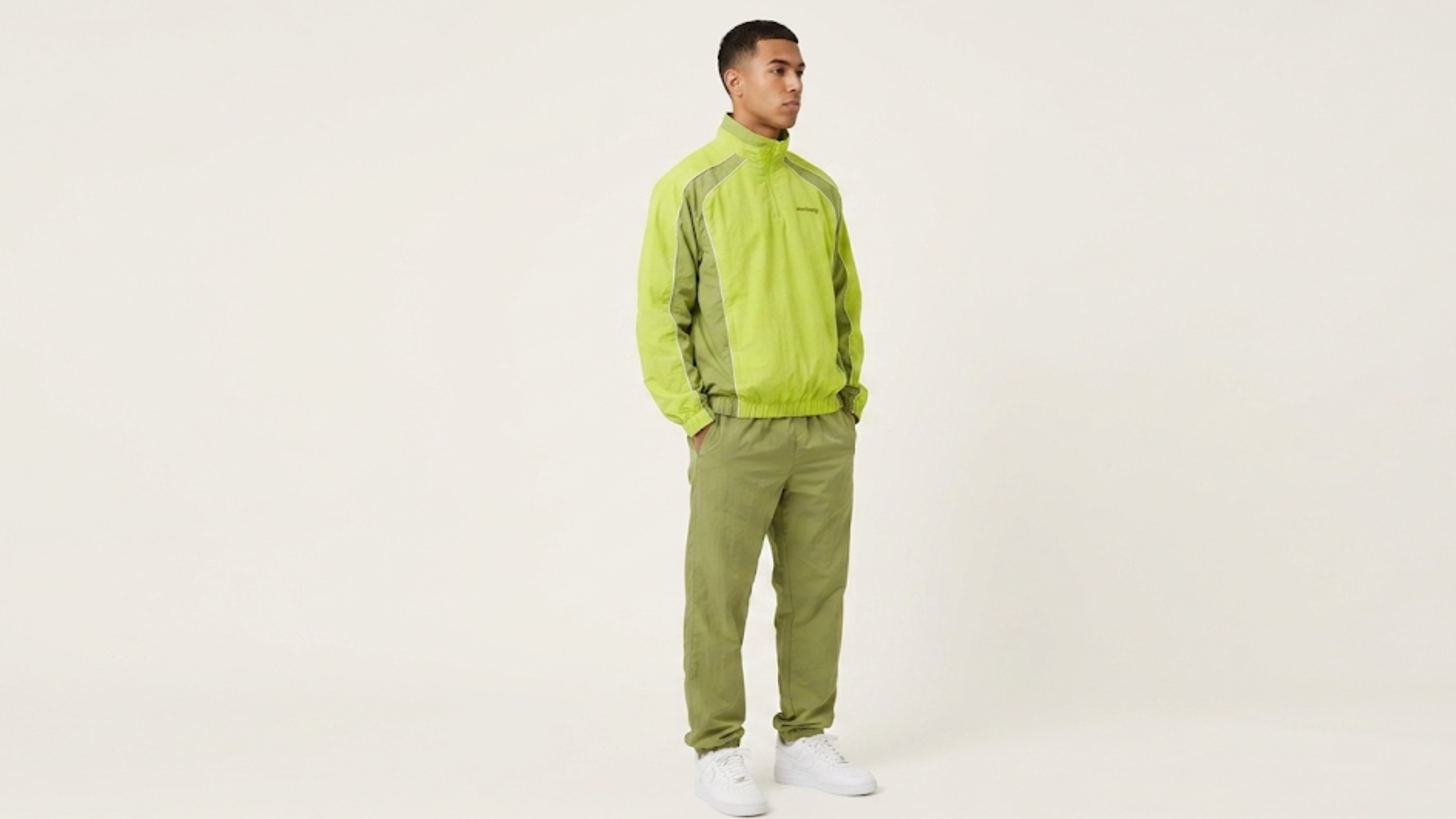 Awake NY quarter zip track jacket in black, green, and blue with stand collar, white piping, and athletic panel design