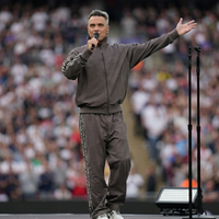 Robbie Williams Soccer Aid 2026 Brown Tracksuit with funnel neck zip jacket and wide-leg pants featuring chain-link side stripe detailing