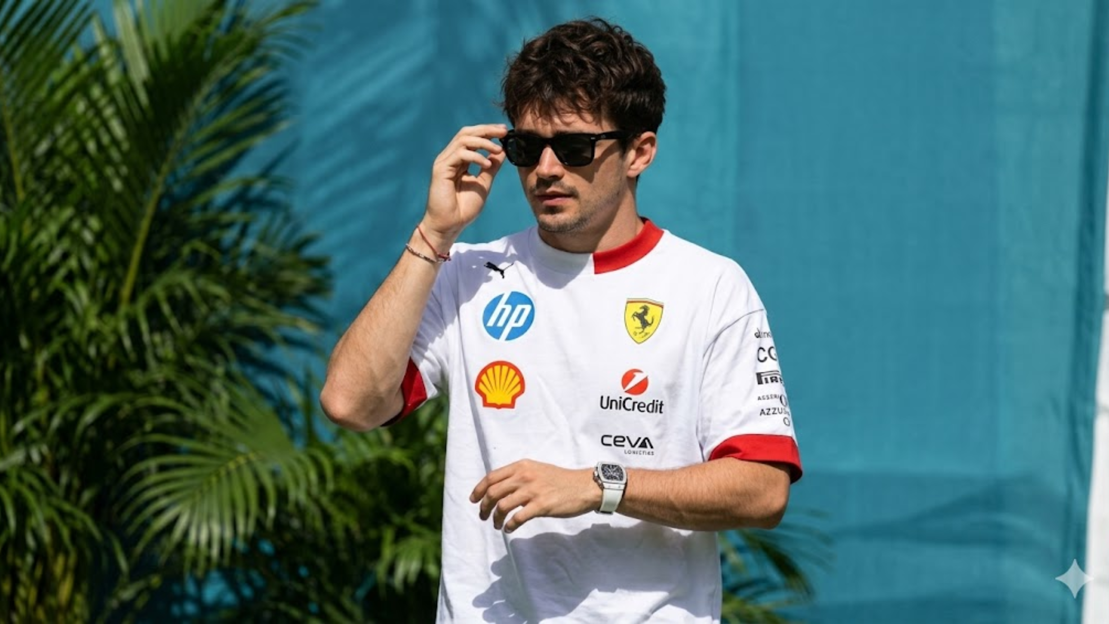 Charles Leclerc in the official white Scuderia Ferrari 2025 Miami GP T-shirt wearing sunglasses against a teal background.
