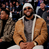 Kayvon Thibodeaux wearing a brown suede shearling jacket with quilted detailing and embroidered accents at the New York Knicks vs. Charlotte Hornets game courtside.