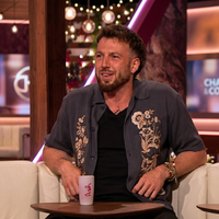 Sam Thompson embroidered grey short-sleeve shirt from Love Island UK Aftersun Season 12 styled over a black tee with floral embroidery detail