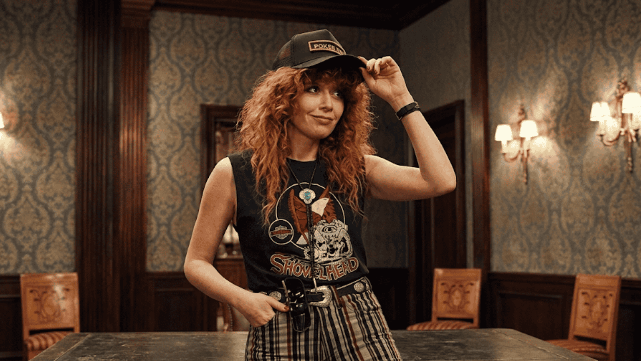 Natasha Lyonne as Charlie Cale in Poker Face wearing a black graphic tank top with a vintage Shovelhead chopper engine print across the front.