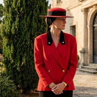 Princess Diana wearing a red contrast collar blazer with black velvet detailing and a boater hat during her 1987 Normandy visit