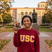 Nemesis S01 Gabrielle Dennis USC Trojans oversized burgundy varsity sweatshirt featuring bold collegiate graphics styled in a casual streetwear look