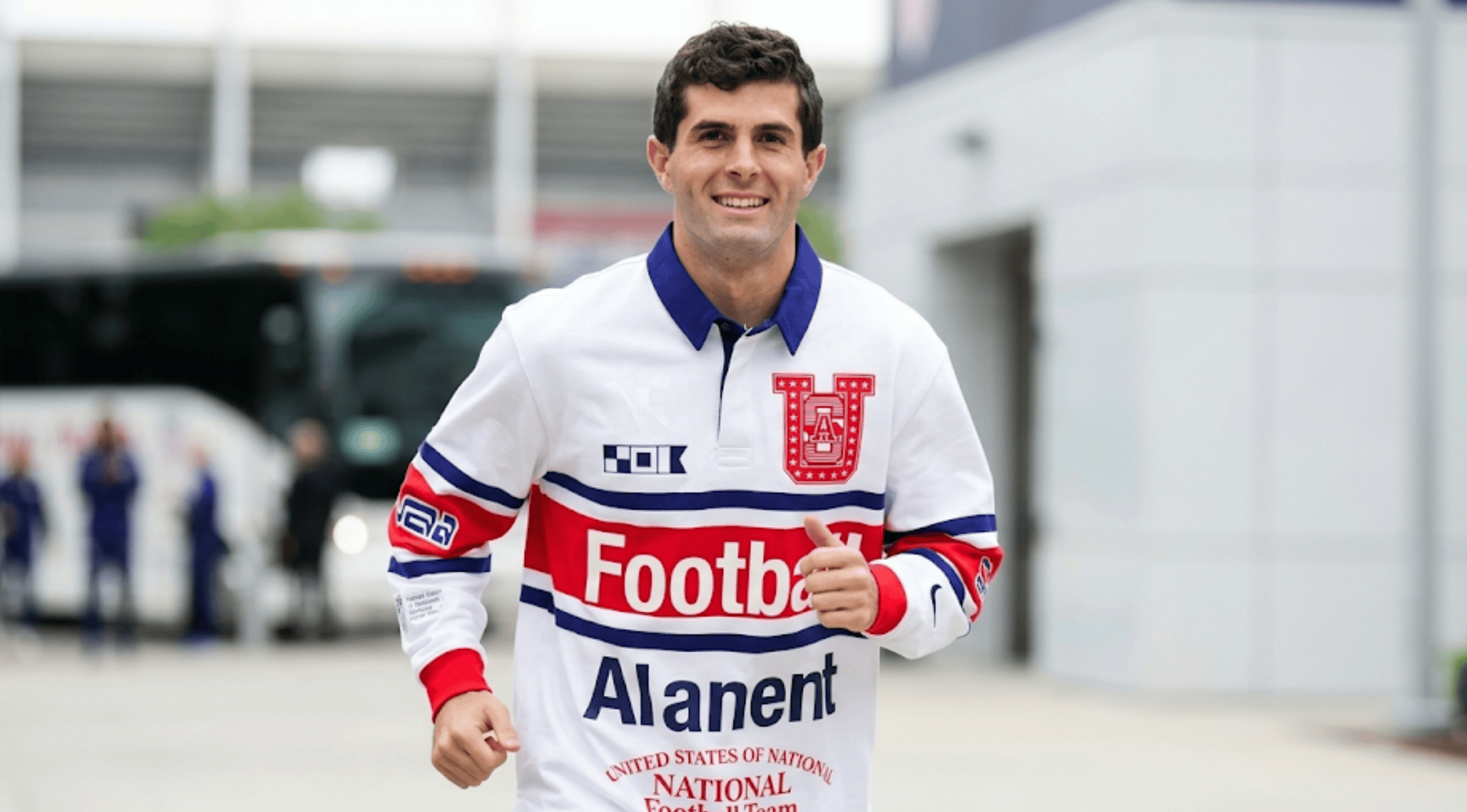 A man wearing the Virgil Abloh Archive Team USA white long-sleeve rugby polo shirt featuring patriotic "Football" graphics, running outdoors smiling.