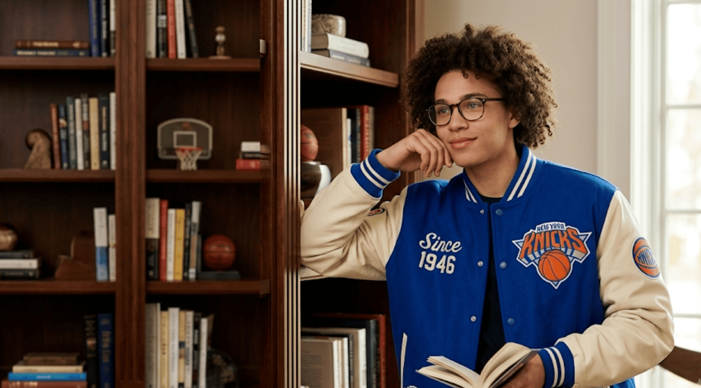 Egypt Dean wearing a royal blue and cream New York Knicks 2026 victory parade varsity jacket with team logo patches
